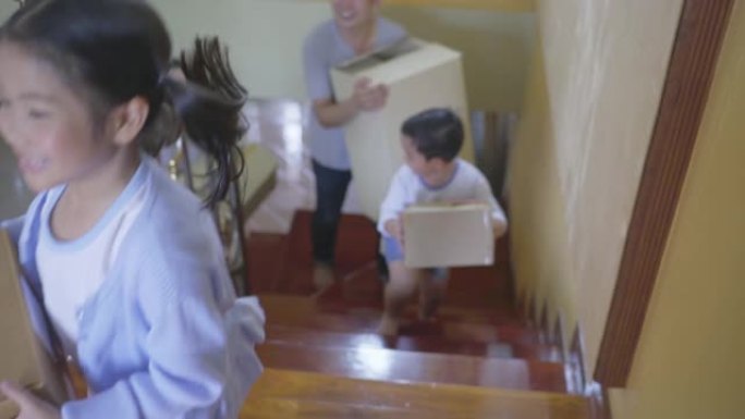 亚洲家庭背着纸板箱，走上新房子的楼梯，慢动作