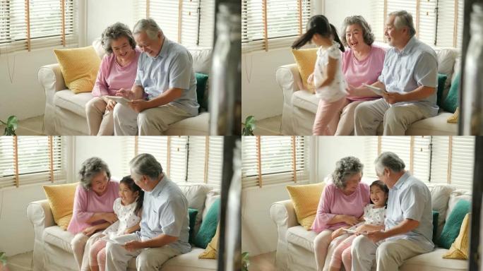 小女孩在玩平板电脑时拥抱她的祖父和祖父。孩子带着快乐的情感和高级男女一起玩。有家庭、生活方式、科技观