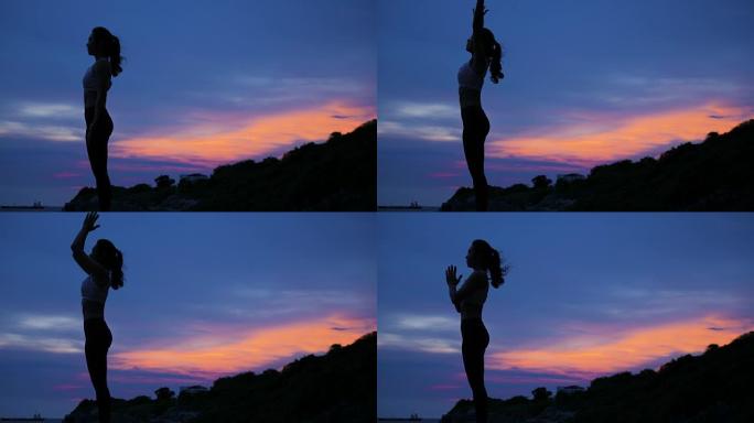 剪影年轻女子站立瑜伽在日落时在海滩上摆姿势，日出背景。健身、运动、瑜伽和健康生活理念。
