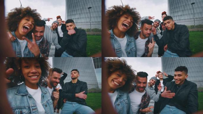 一群不同种族的年轻朋友的慢动作在摩天大楼的市中心玩得开心，并用手机自拍