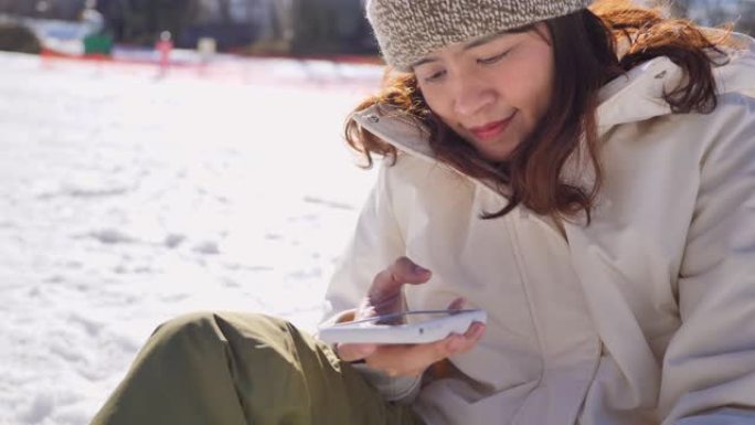 年轻女子在滑雪胜地用智能手机自拍