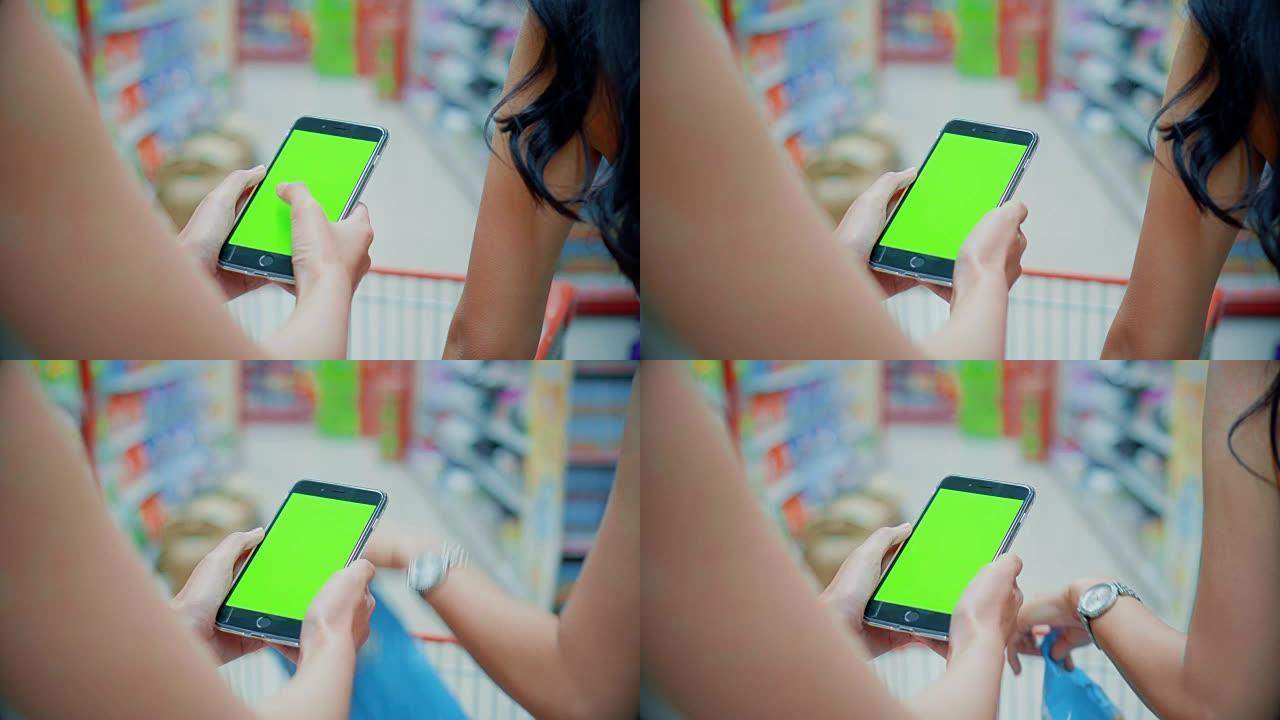 两名年轻女性在超市使用智能手机，绿屏
