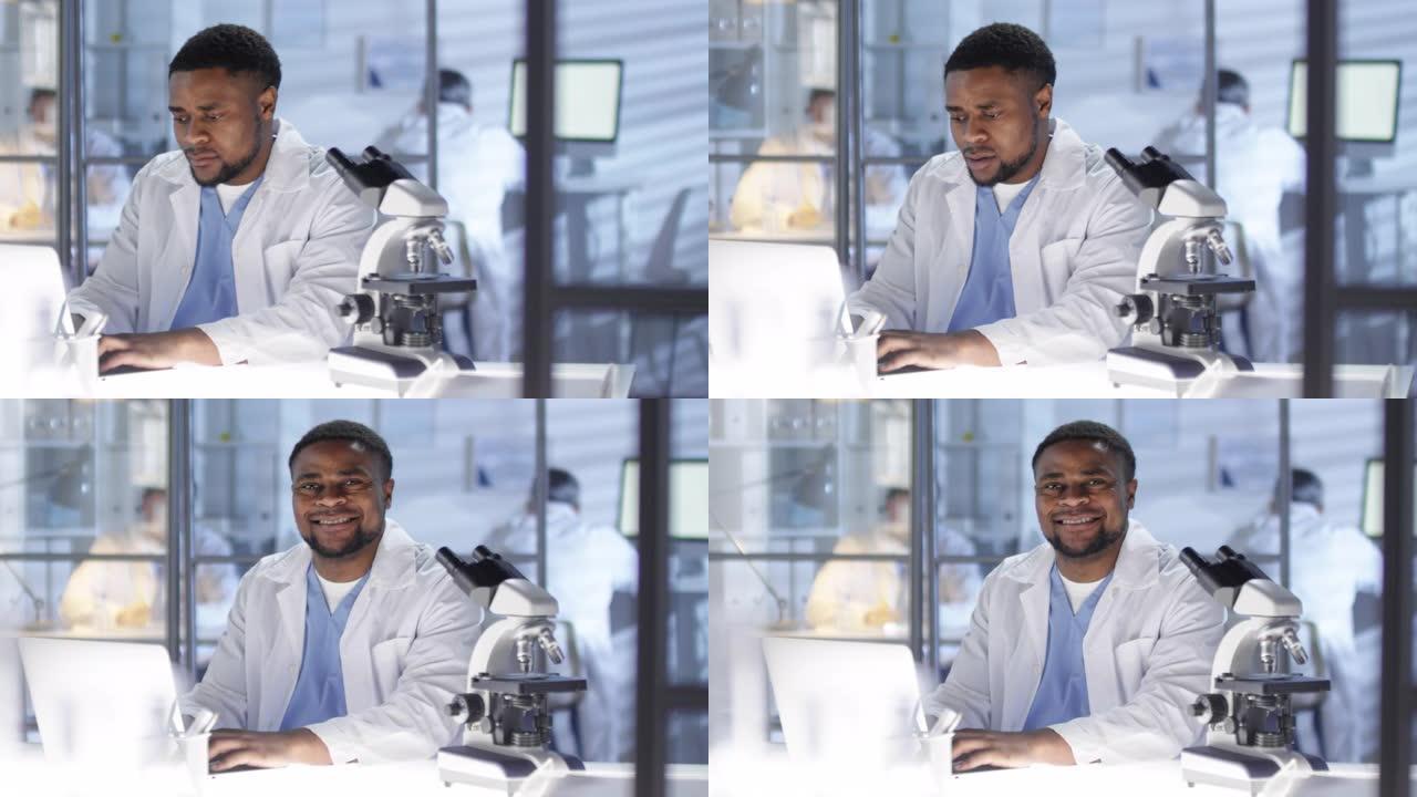 美国黑人研究人员在笔记本电脑上工作，并为相机微笑