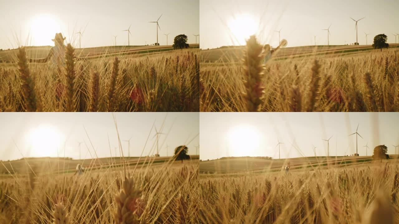戴着太阳帽的女人跑过麦田，远处有风力涡轮机