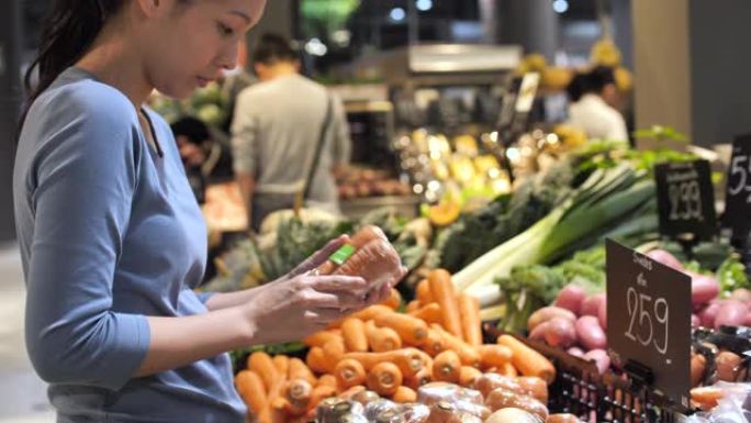 亚洲妇女在超市选择蔬菜