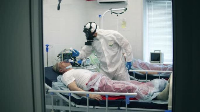 护理人员正在检查一名戴着氧气面罩的男子的温度