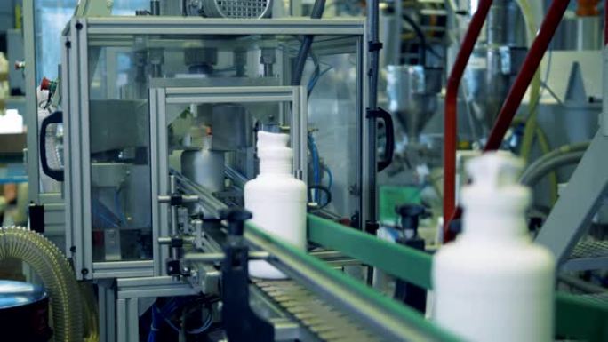 工厂输送机上带有化学药品的白色瓶子，自动技术。