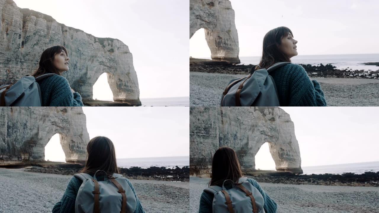 快乐兴奋美丽的旅游女人在埃特雷塔慢动作附近的阳光海滩探索美丽的白色拱形岩石。