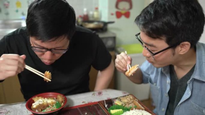 两个快乐的朋友在家里吃日本便当盒