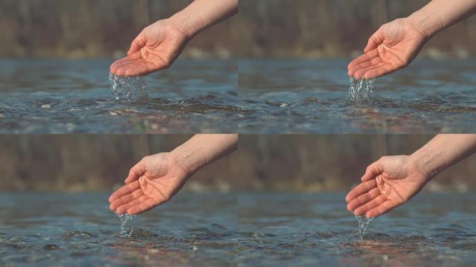 慢动作: 无法辨认的女孩温柔的手溅起玻璃状的河水。