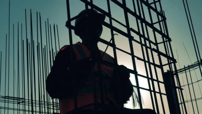 穿着制服的人在建筑工地编织钢筋。