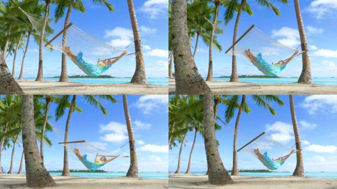 低角度: 熟睡的女人在热带白色沙滩上的绳索吊床上晃来晃去。