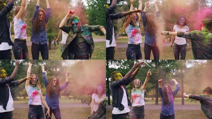快乐的男女在公园的草坪上跳跃、大笑和扔五颜六色的粉末。青年文化和活动理念。