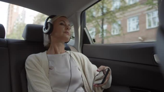 戴着耳机的女人透过车窗看，在电话上听音乐