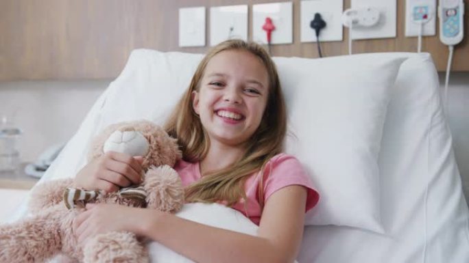 母亲探望女儿躺在医院病房的床上，给她泰迪熊