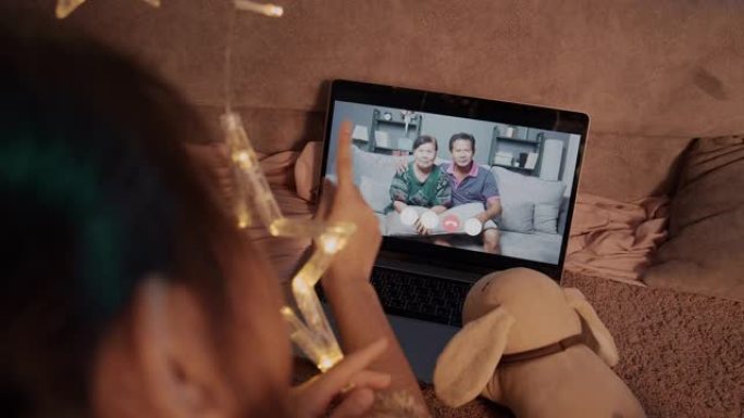 亚洲女孩使用笔记本电脑进行视频通话，并与她的祖父和祖母在家里的客厅冠状病毒锁定情况保持距离。技术和社