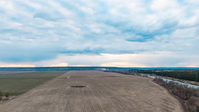无人机拍摄美丽的乡村风景，培育绿色的田野和彩色的日落地平线，黄色的蓝天快速移动的云，时间流逝的运动