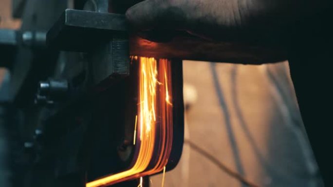 铁匠在锻造厂工作时使用角磨机。