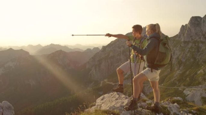 慢动作: 活跃的夫妇从阿尔卑斯山的一座山峰上观察日落。