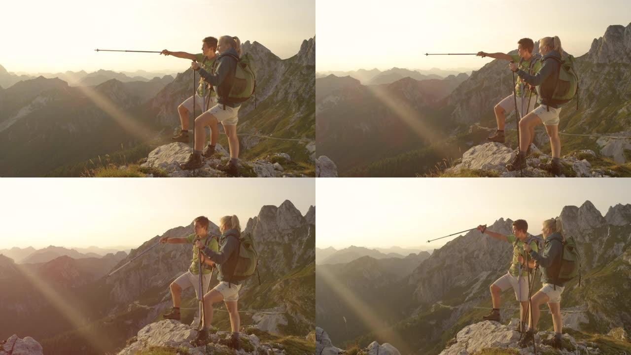 慢动作: 活跃的夫妇从阿尔卑斯山的一座山峰上观察日落。