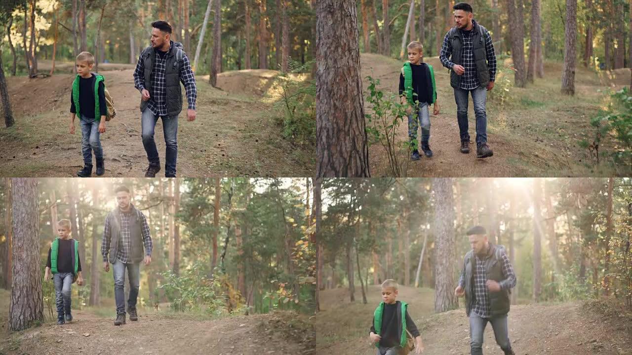 英俊的年轻人和他可爱的小儿子正在森林里散步，聊天享受新鲜的空气、自然和交流。家庭、父亲和旅游概念。
