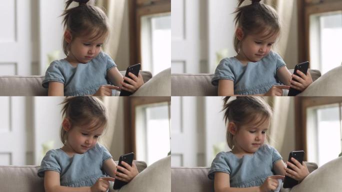 可爱的聪明的小女孩独自在家使用智能手机