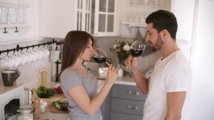幸福的夫妇在厨房喝酒接吻