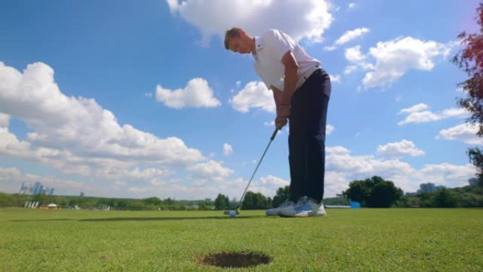 职业高尔夫球手在草地上将球打入洞中。