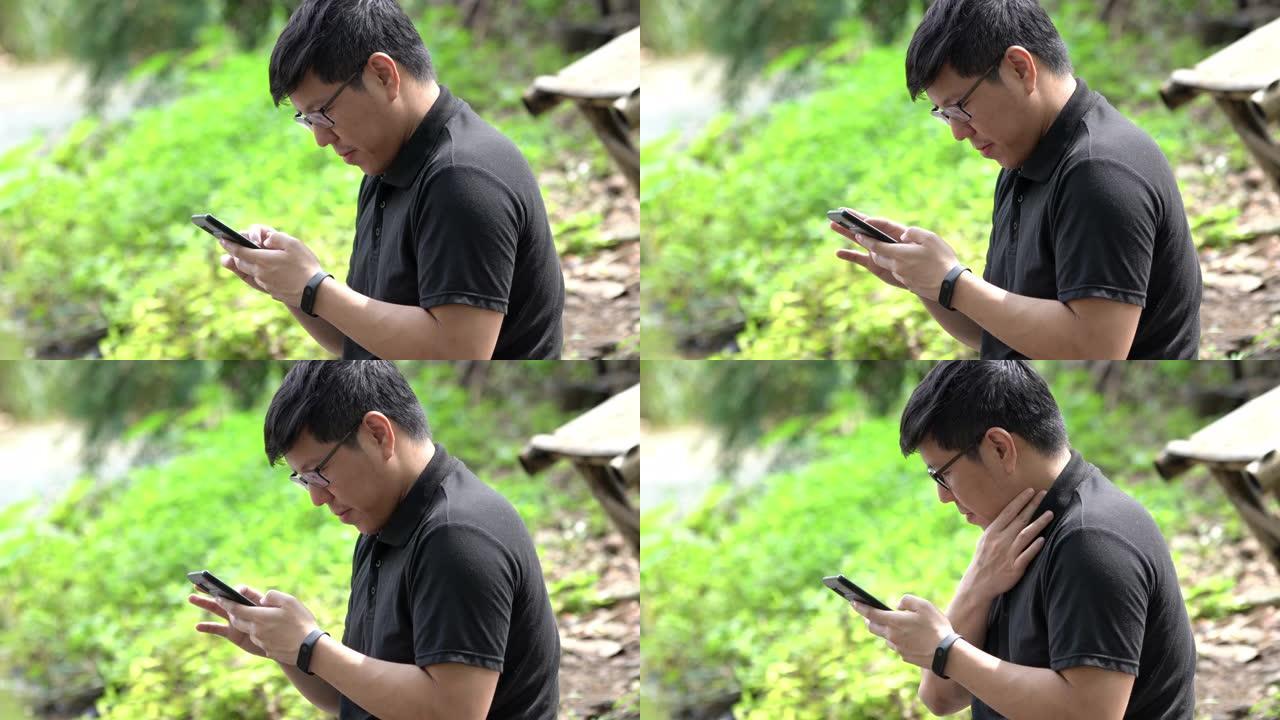 亚洲男子放松在典型的河流玩智能手机