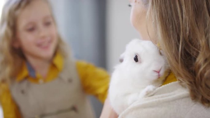 母亲抱着的女孩抚摸兔子