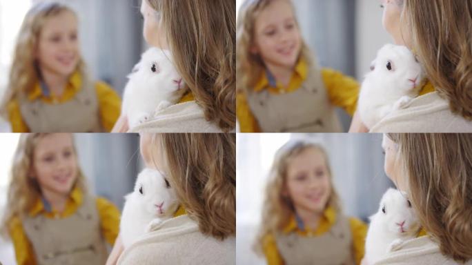 母亲抱着的女孩抚摸兔子