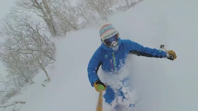 自拍照: 年轻的自由滑雪者切碎了日本山区的深雪。