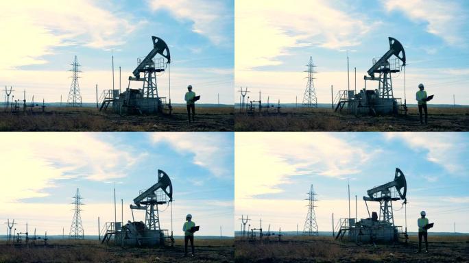 一个人带着石油井架走在田野上。石油开采行业概念。