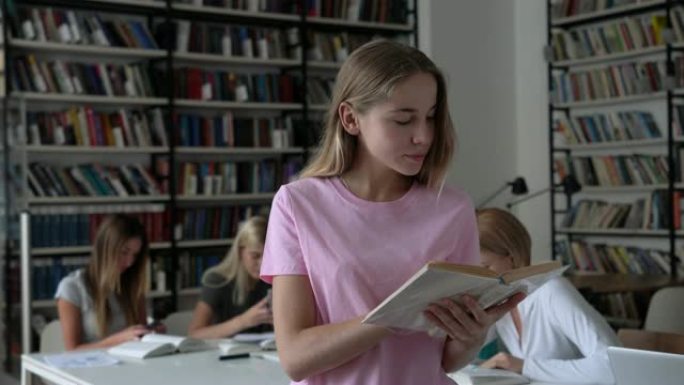 美丽的年轻女子在读书时微笑着读书，而其他学生则在图书馆里