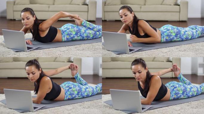 女人伸展四肢并在笔记本电脑上观看瑜伽锻炼