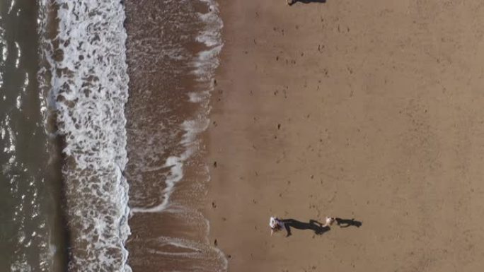 通过破浪在海滩上度假的家庭拍摄的无人机