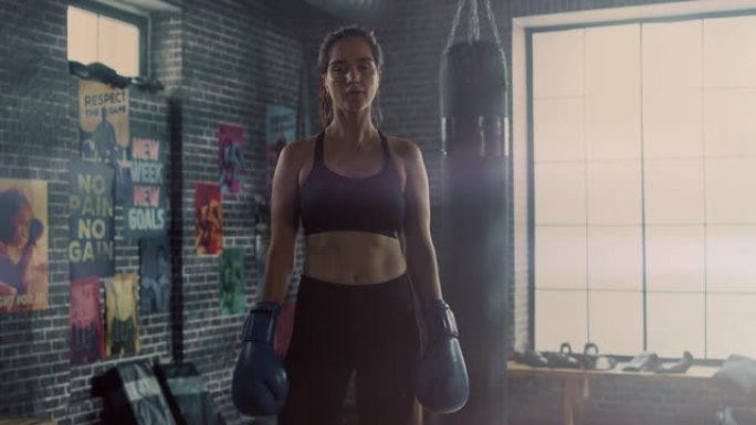 一位美丽健康的黑发跆拳道运动员站在阁楼健身房的肖像，上面贴着激励海报。经过激烈的健身训练后，她喘不过
