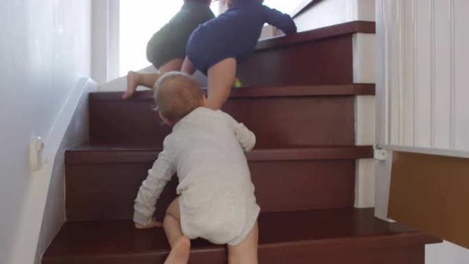 婴儿三胞胎在家里朝妈妈爬上楼梯