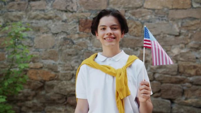 肖像迷人的美国少年户外与美国国旗微笑