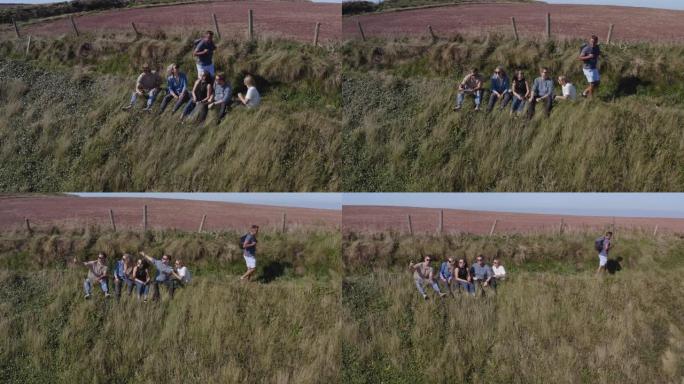 一群朋友在沿海小径上的悬崖上徒步旅行的无人机拍摄