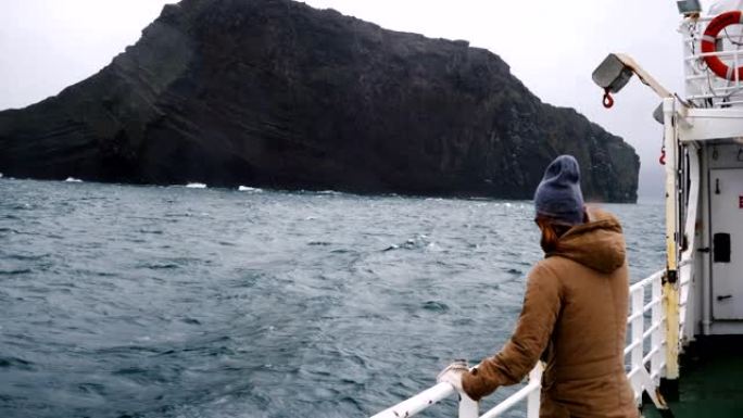 年轻漂亮的女人站在船上。在阴天独自探索冰岛的女性旅行
