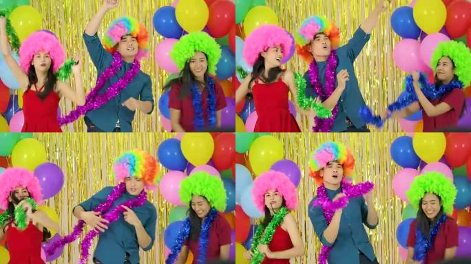 朋友们在派对上以慢动作带着五颜六色的气球背景快乐地跳舞。
