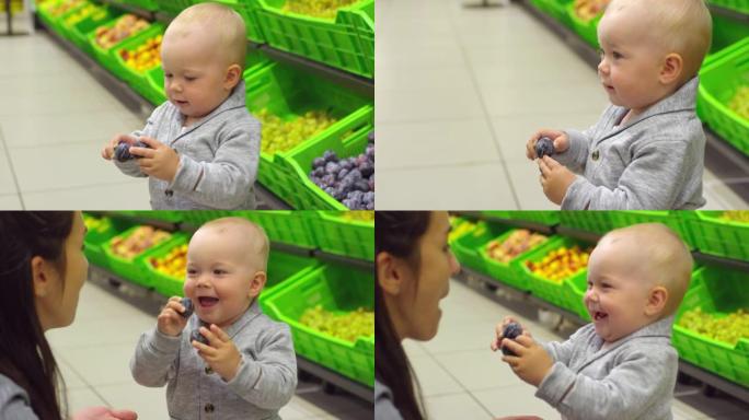 可爱的蹒跚学步的孩子在超市吃李子
