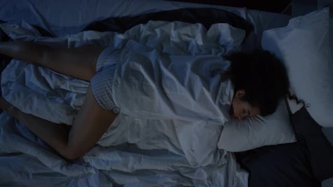 穿着睡衣睡在黑暗卧室的女人的高角度镜头