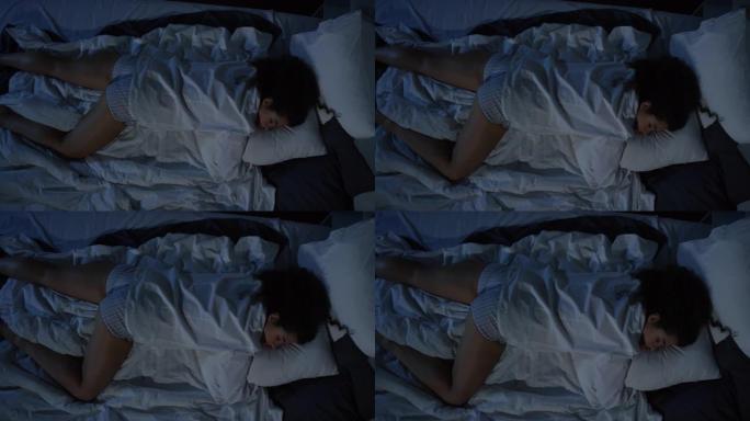 穿着睡衣睡在黑暗卧室的女人的高角度镜头