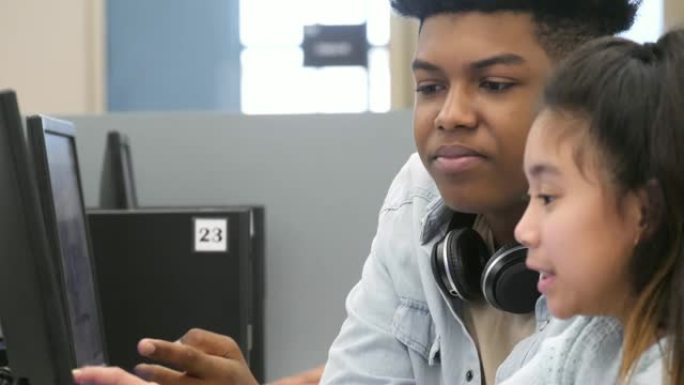 十几岁的男孩在计算机实验室辅导小学女生