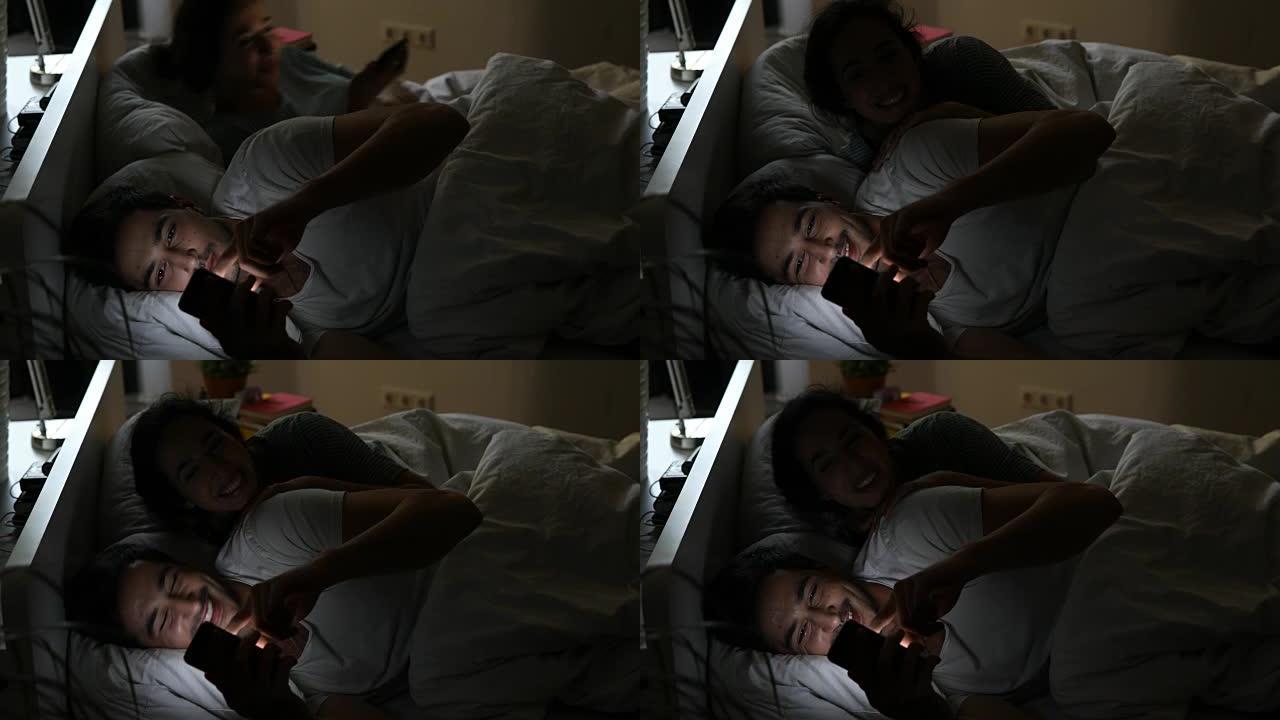 幸福的夫妻在床上看手机