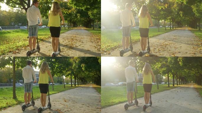 镜头耀斑: 无忧无虑的情侣在阳光明媚的秋日骑电动滑板车。