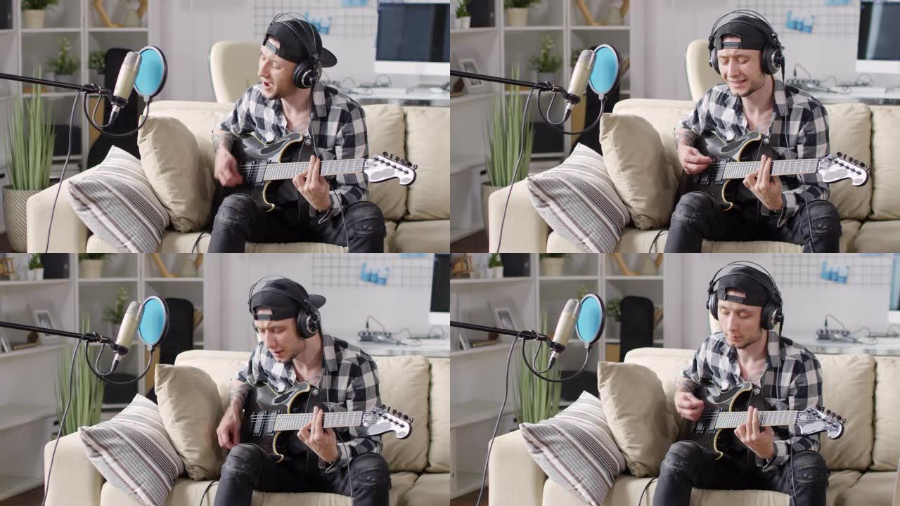 年轻人在沙发上弹吉他和录制歌曲