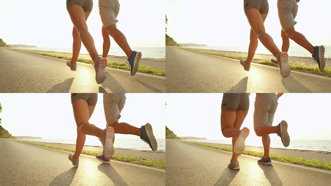 慢动作: 运动的年轻男女在风景秀丽的沿海公路上奔跑。